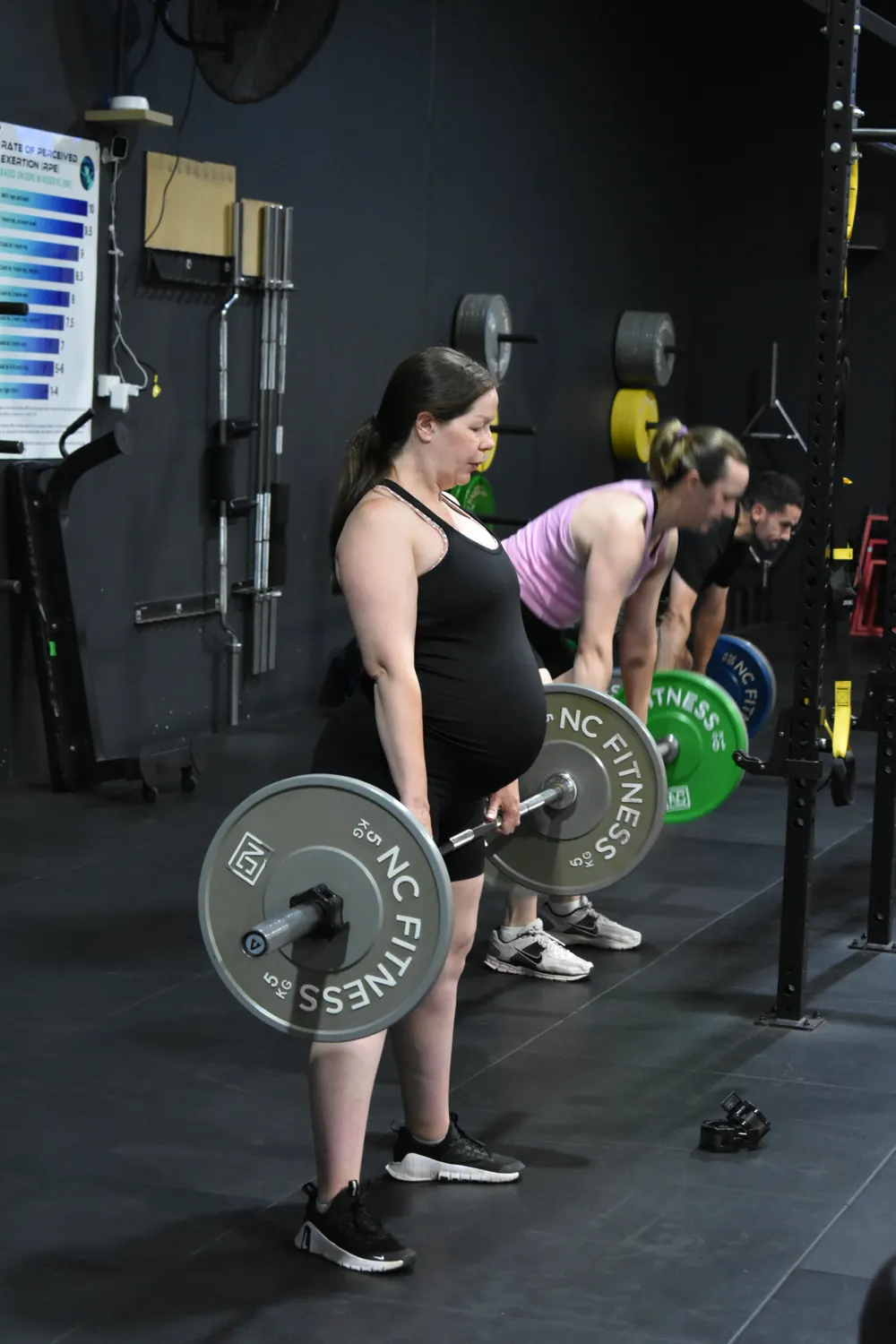 Member deadlifting a barbell in a coached session