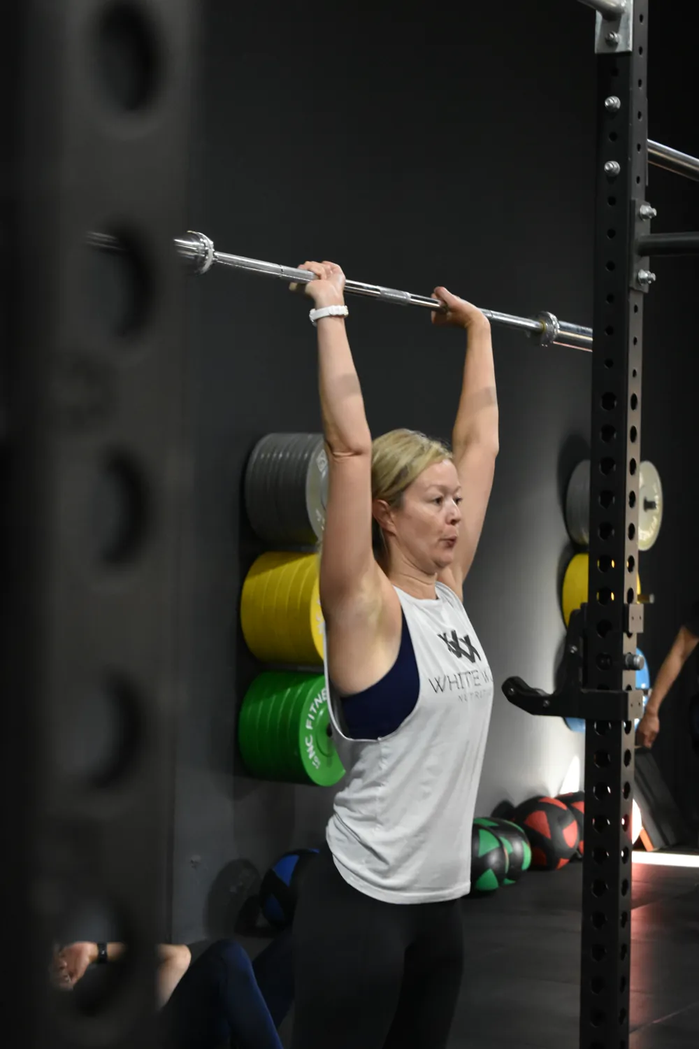 Member pressing dumbbells overhead