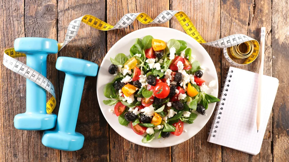 Salad, dumbbells and a notebook